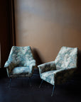 Pair of vintage Italian mid-century modern armchairs with curved backrests and floral tapestry upholstery on tapered metal legs with brass feet.
