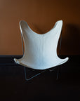 Authentic original 1960s Knoll BKF Butterfly Chair designed by Ferrari-Hardoy with an off-white French linen canvas cover against a brown wall.