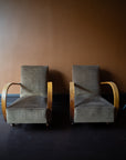 Pair of vintage French Art Deco armchairs from Avignon with sweeping bentwood armrests and olive bronze velvet upholstery against a brown wall.