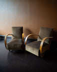 Pair of vintage French Art Deco armchairs from Avignon with sweeping bentwood armrests and olive bronze velvet upholstery against a brown wall.