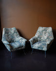 Pair of vintage Italian mid-century modern armchairs with curved backrests and floral tapestry upholstery on tapered metal legs with brass feet.