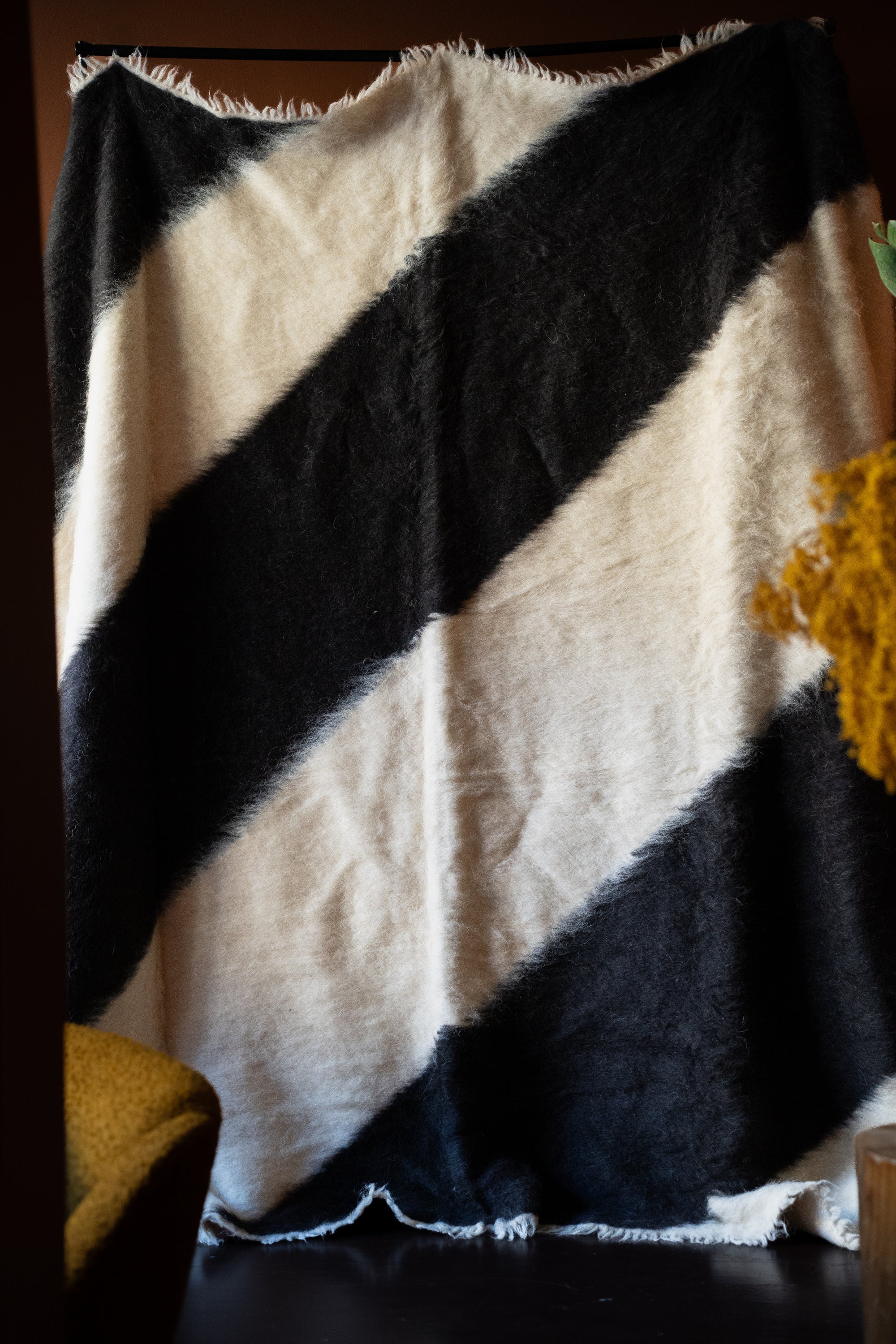 Marie Olsson Nylander hand-tufted Ukrainian wool blanket rug with wide diagonal black and cream graphic blockstripes resembling a traditional Lizhnyk throw.