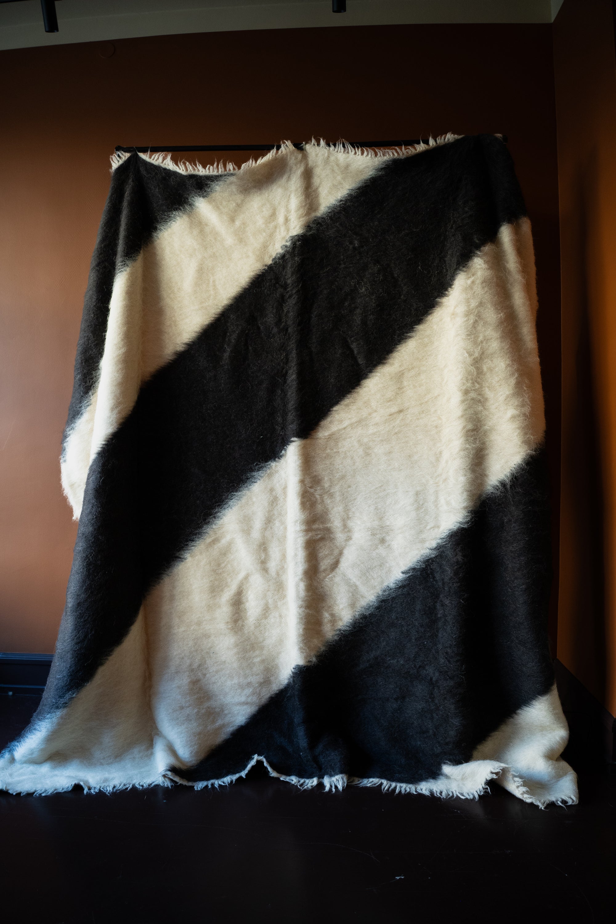 Marie Olsson Nylander hand-tufted Ukrainian wool blanket rug with wide diagonal black and cream graphic blockstripes resembling a traditional Lizhnyk throw.