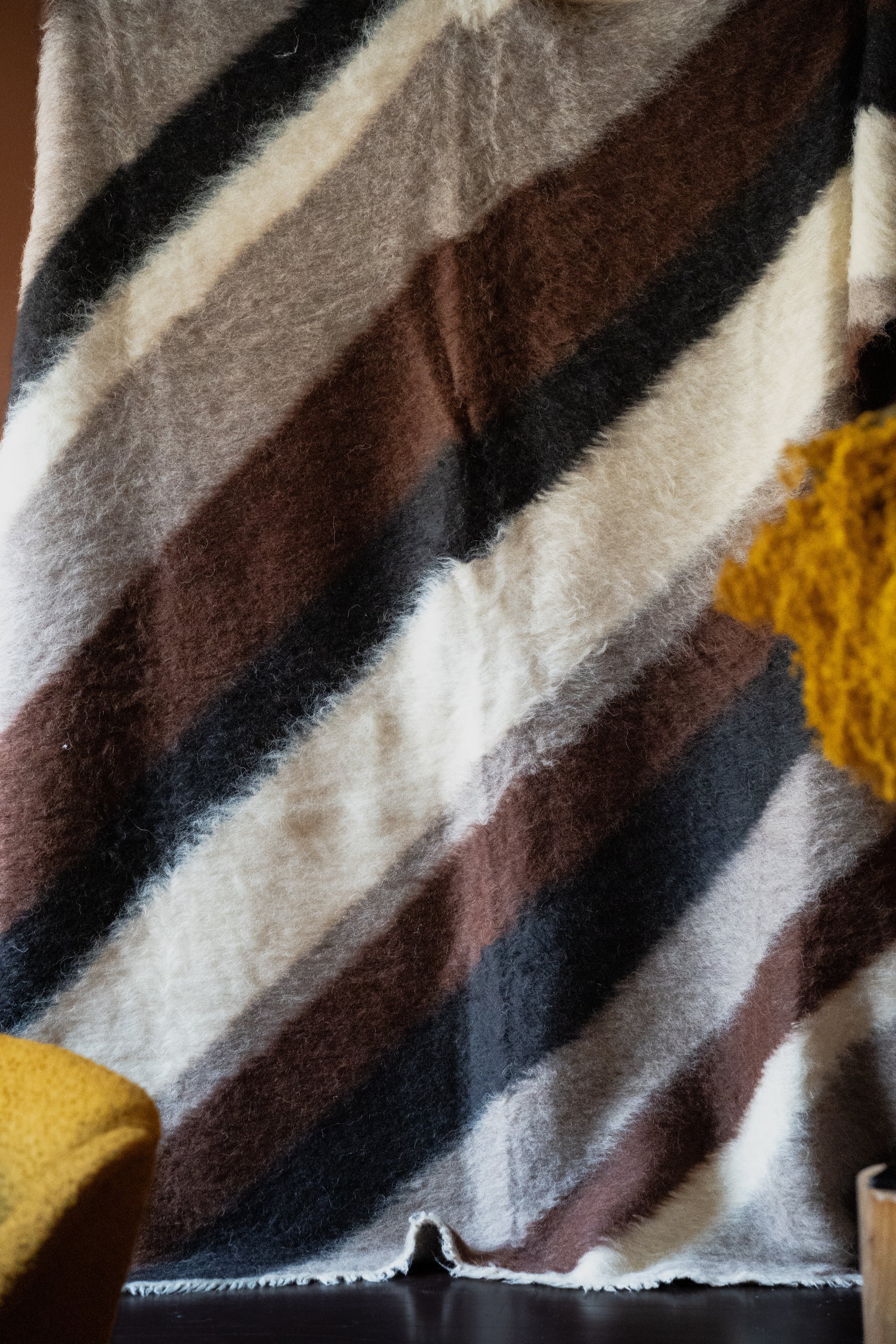 Marie Olsson Nylander hand-tufted Ukrainian wool blanket rug with wide diagonal black and cream graphic blockstripes resembling a traditional Lizhnyk throw.