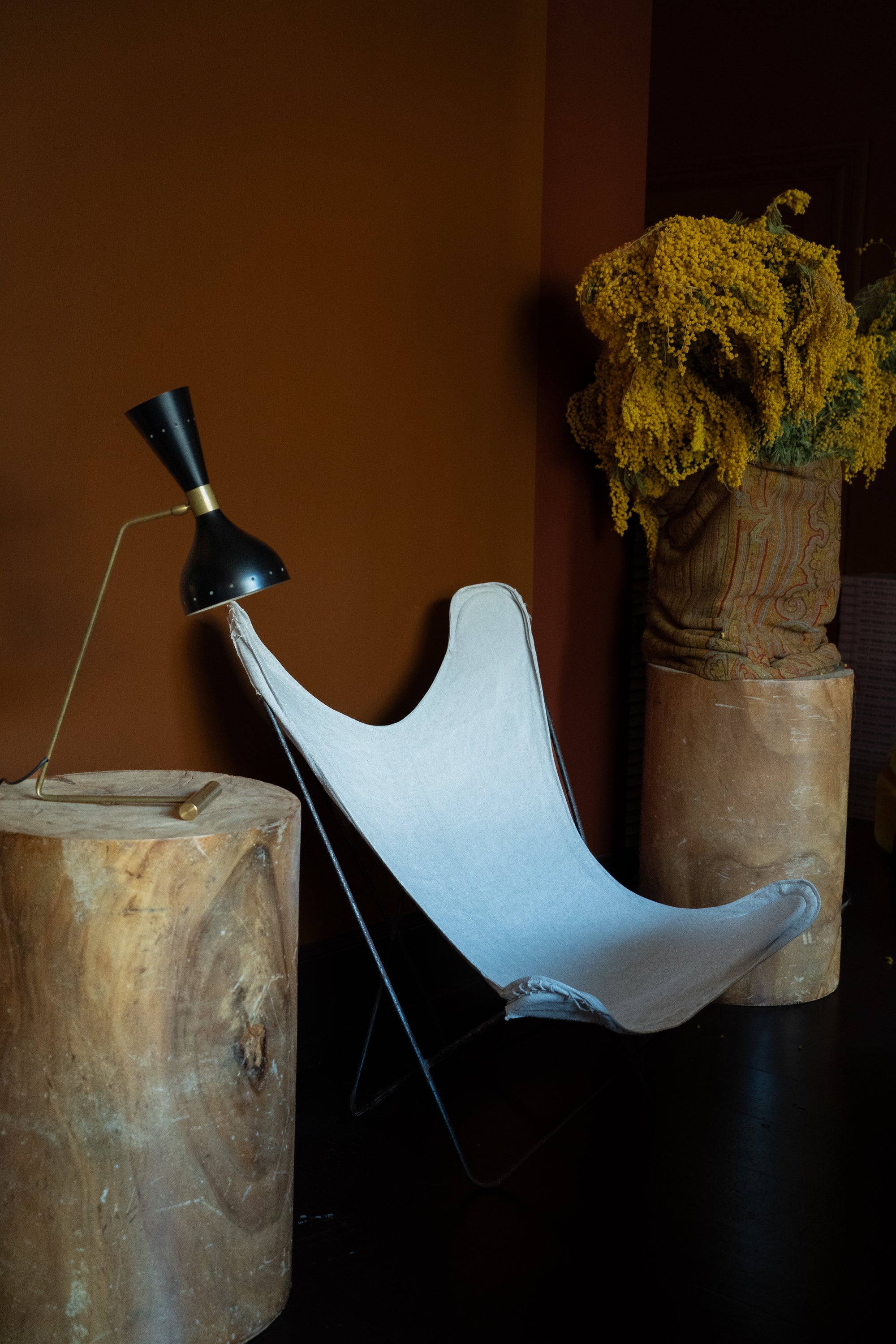 Authentic original 1960s Knoll BKF Butterfly Chair designed by Ferrari-Hardoy with an off-white French linen canvas cover against a brown wall.