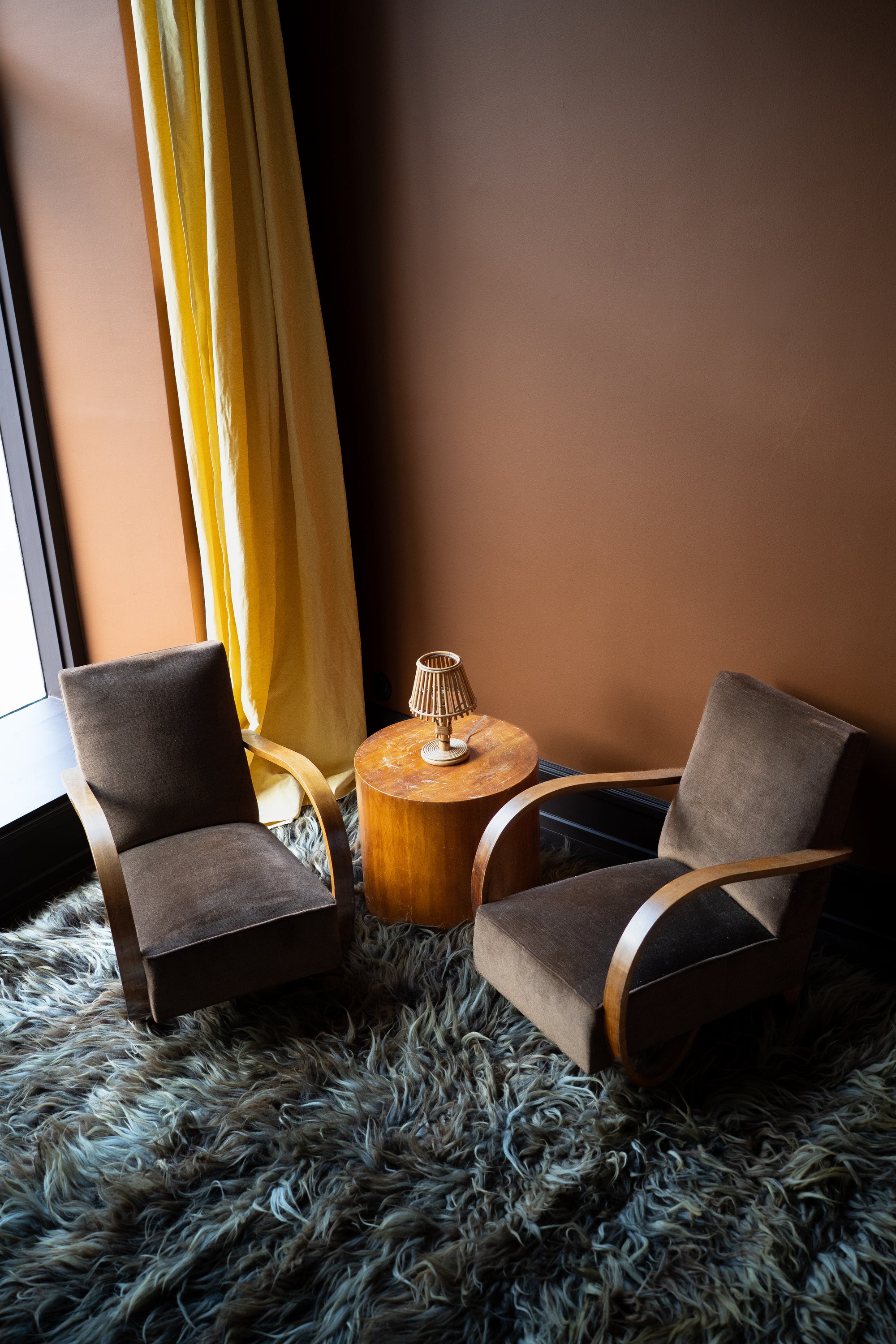 Pair of vintage French Art Deco armchairs from Avignon with sweeping bentwood armrests and olive bronze velvet upholstery against a brown wall.