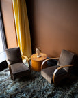 Pair of vintage French Art Deco armchairs from Avignon with sweeping bentwood armrests and olive bronze velvet upholstery against a brown wall.