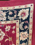 Semi-antique Indian quilt with a deep rust red base, ornate cream floral motifs, and a dark blue patterned border.
