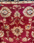 Semi-antique Indian quilt with a deep rust red base, ornate cream floral motifs, and a dark blue patterned border.